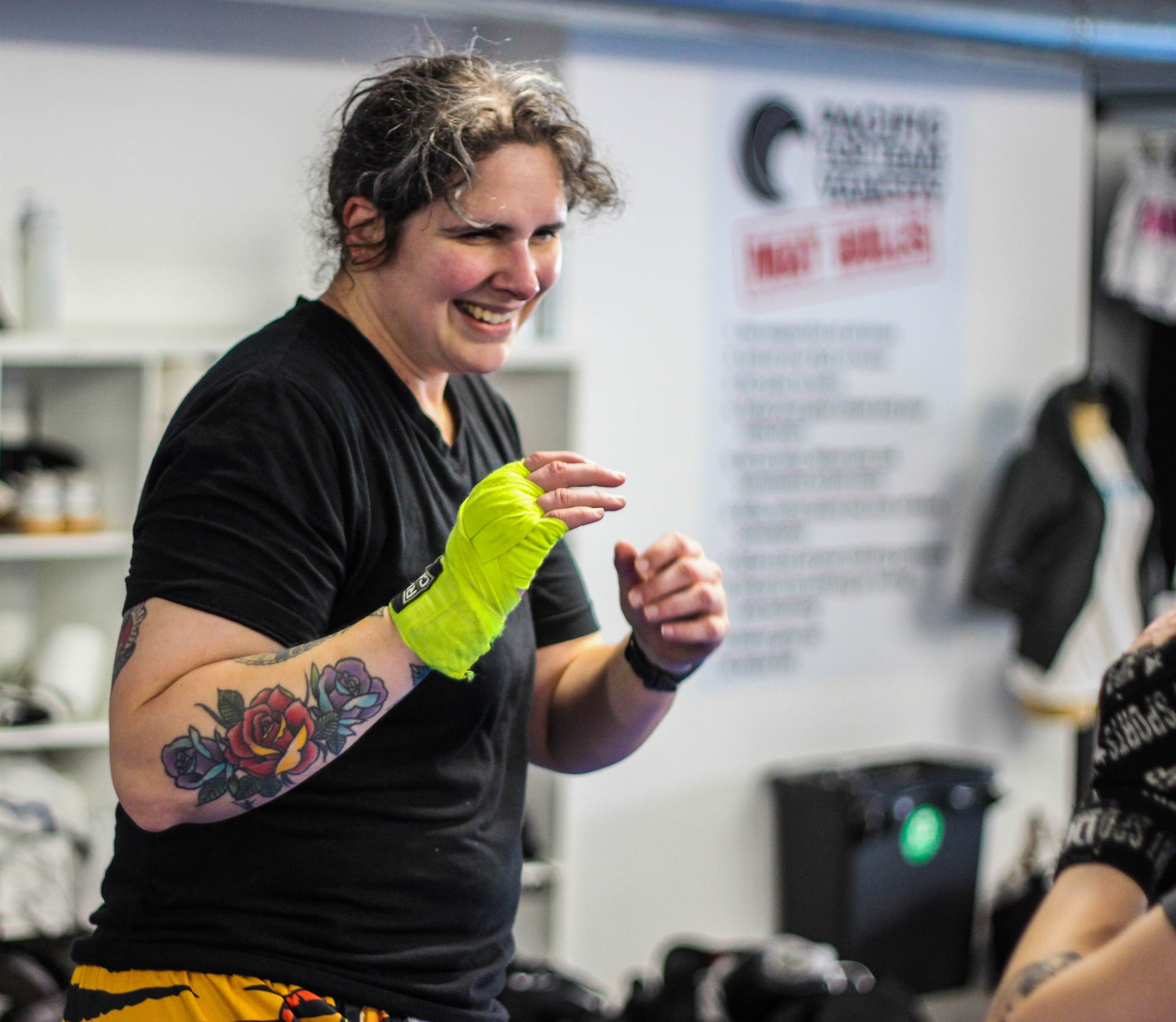 Adult student with neon yellow hand wraps holding a boxing stance during Muay Thai training