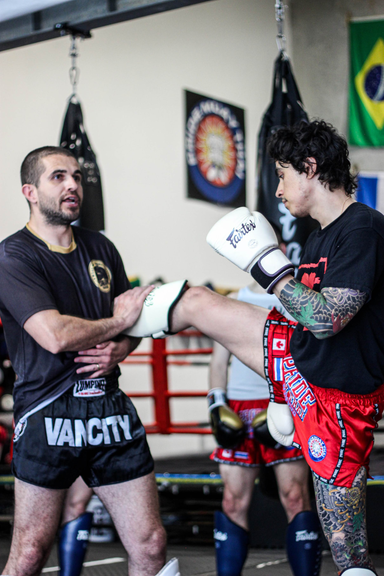 Coach guiding a beginner student through a Muay Thai technique step by step