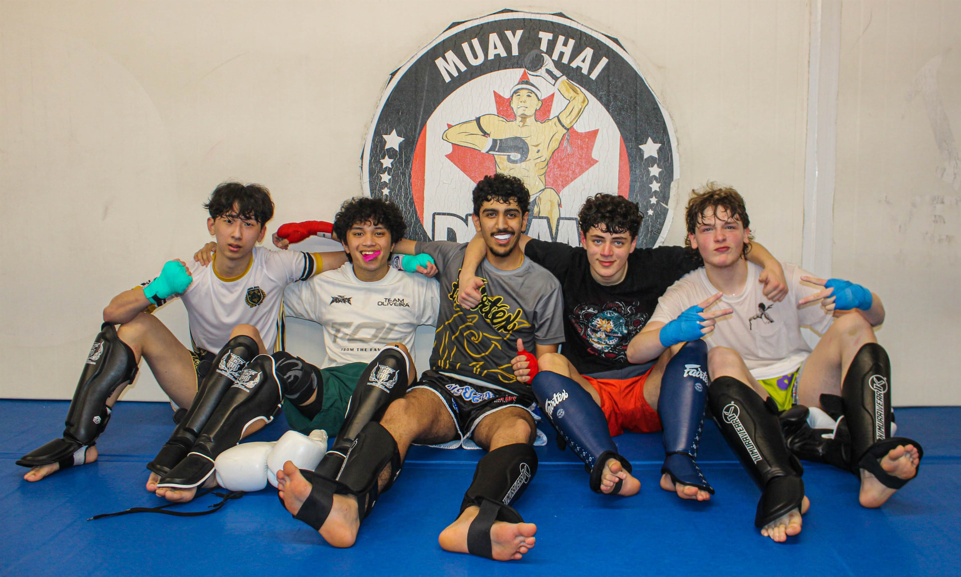Group of young students sitting together and smiling after a Muay Thai session